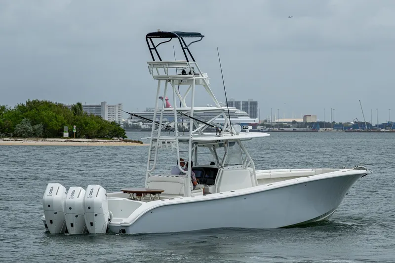  Yacht Photos Pics 2013 Yellowfin 39 Offshore boat with triple engines cruising near a city shoreline.