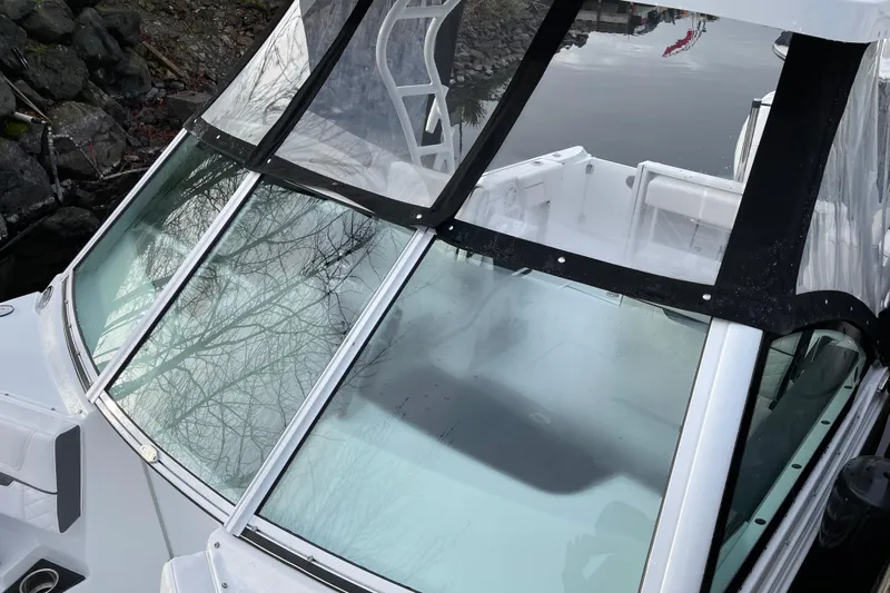 Yacht Photos Pics 2021 Blackfin 252DC boat with clear windshield, docked near rocky shoreline.