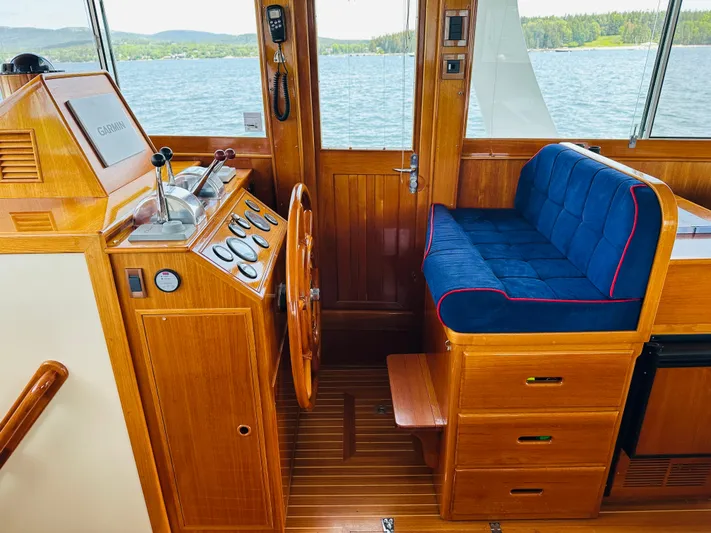 Liberty Yacht Photos Pics Grand Banks 46 Europa 2003 yacht helm with wooden steering wheel and blue cushioned seating.