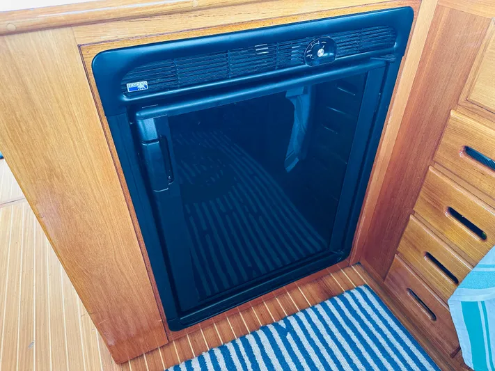 Liberty Yacht Photos Pics Built-in refrigerator on 2003 Grand Banks 46 Europa yacht, wooden cabinetry, striped rug.