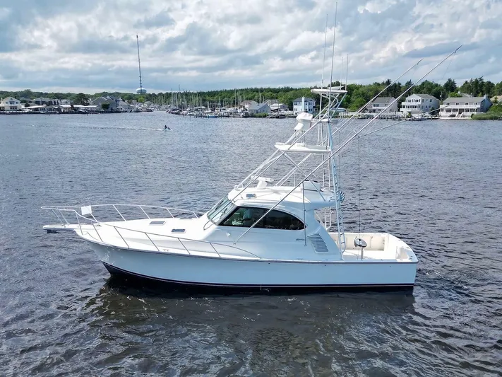  Yacht Photos Pics 2022 Henriques 42 Express Hardtop boat on calm water, with coastal houses in the background.