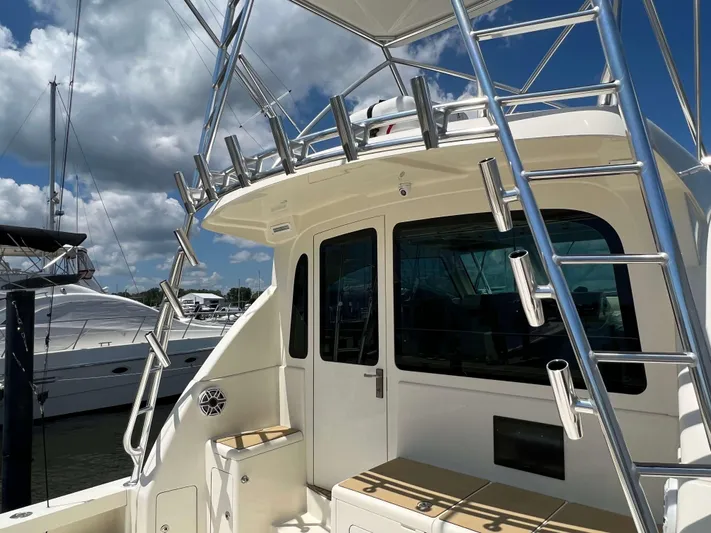 Yacht Photos Pics 2022 Henriques 42 Express Hardtop boat with ladder and seating, docked under a cloudy sky.