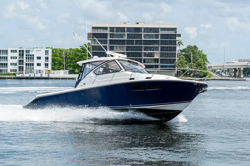  Yacht Photos Pics Pursuit boat cruising on water near modern buildings and bridge.