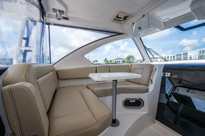  Yacht Photos Pics Luxurious Pursuit boat interior with beige seating and a white table, under a clear sky.