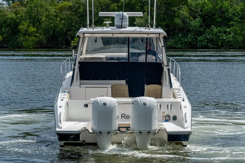  Yacht Photos Pics Rear view of a Pursuit boat with dual outboard motors on a calm river.
