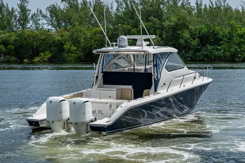  Yacht Photos Pics Luxury Pursuit boat cruising on a serene waterway, surrounded by lush greenery.