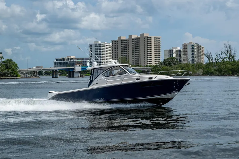  Yacht Photos Pics Pursuit boat cruising on water with city skyline in the background.