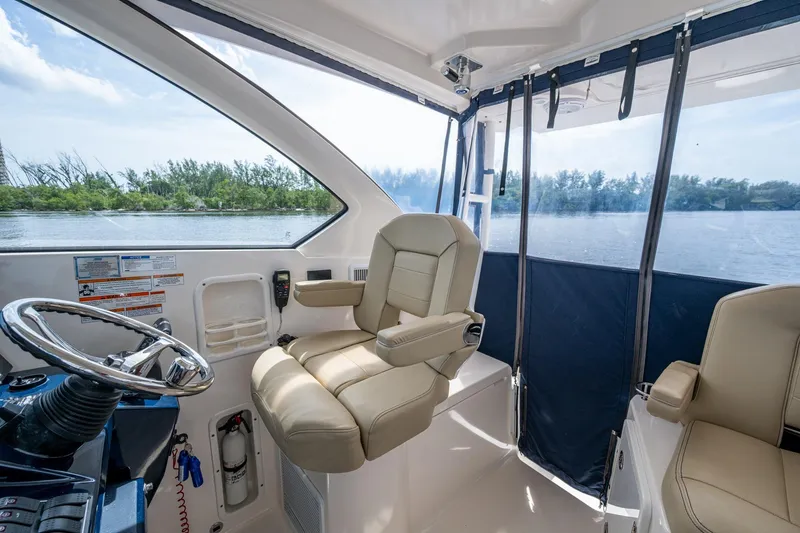  Yacht Photos Pics Interior of a Pursuit boat with beige seating and steering wheel, overlooking calm waters.