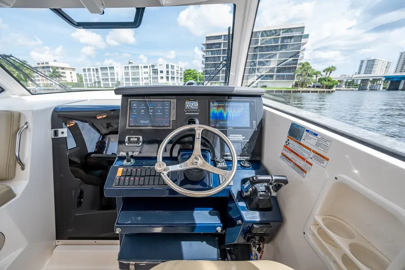  Yacht Photos Pics Boat cockpit with steering wheel, digital displays, and waterfront view; Pursuit make.