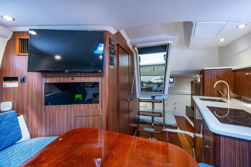  Yacht Photos Pics Luxurious Pursuit boat interior with wood paneling, TV, kitchenette, and seating area.