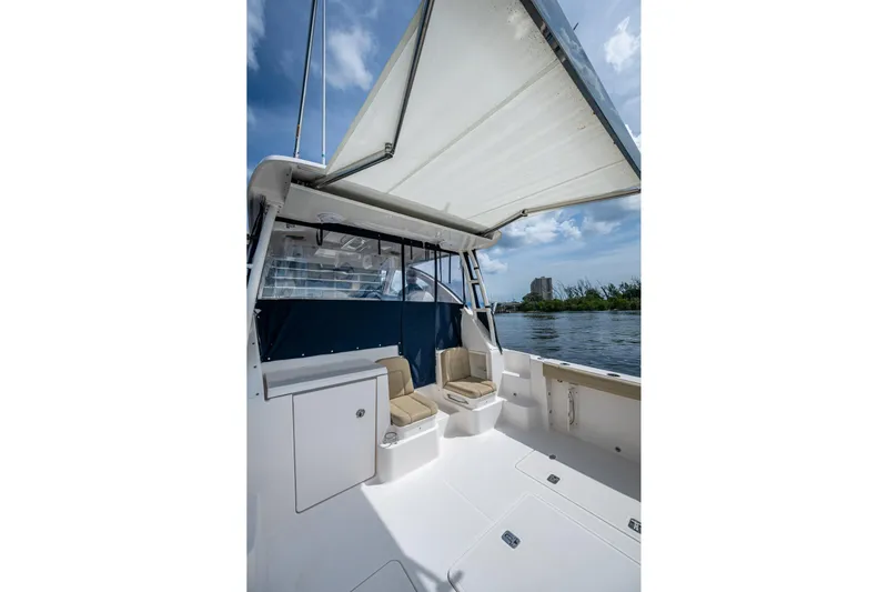  Yacht Photos Pics Pursuit boat interior with seating, canopy, and water view under a blue sky.