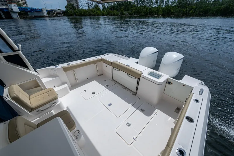  Yacht Photos Pics Spacious Pursuit boat deck with seating, storage, and dual outboard motors on a calm river.