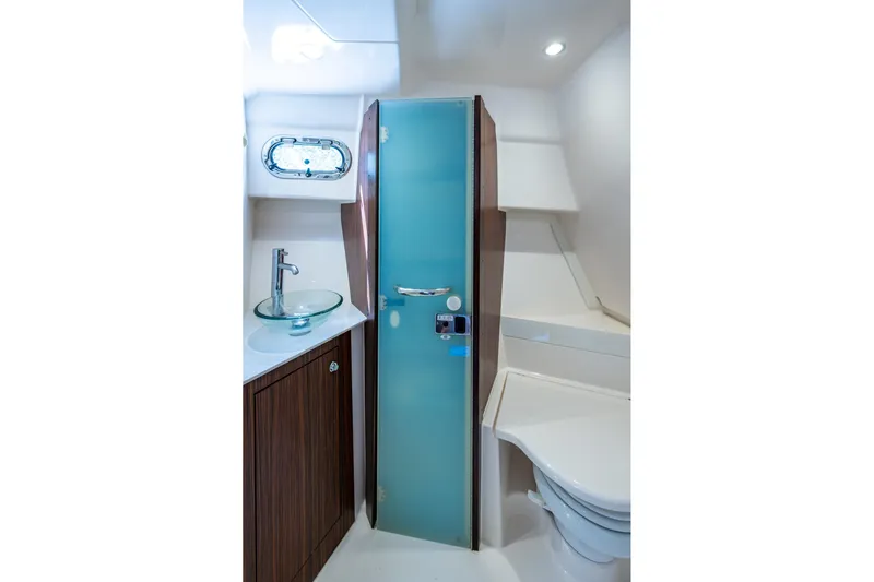  Yacht Photos Pics Modern boat bathroom with glass sink, frosted door, and wooden cabinetry by Pursuit.