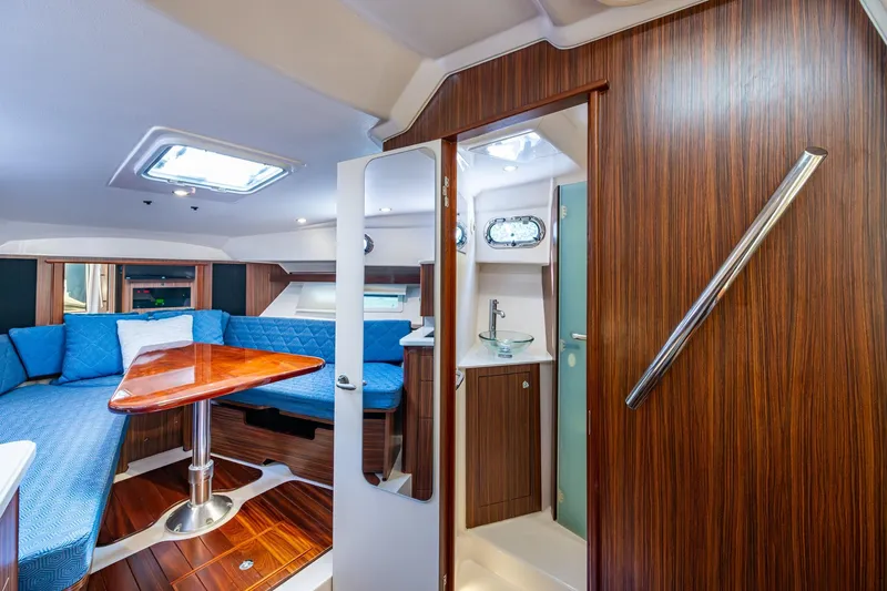  Yacht Photos Pics Luxurious Pursuit boat interior with wood finish, blue seating, and compact bathroom.