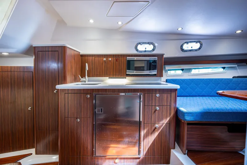  Yacht Photos Pics Luxurious Pursuit yacht interior with wood cabinetry, kitchenette, and blue seating.