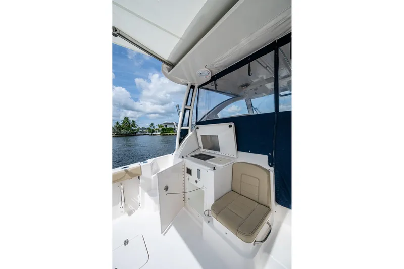  Yacht Photos Pics Interior view of a Pursuit boat with seating and storage, overlooking a scenic waterfront.