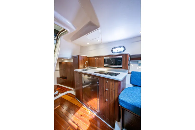  Yacht Photos Pics Luxurious Pursuit yacht interior kitchen with wood cabinetry, modern appliances, and elegant design.