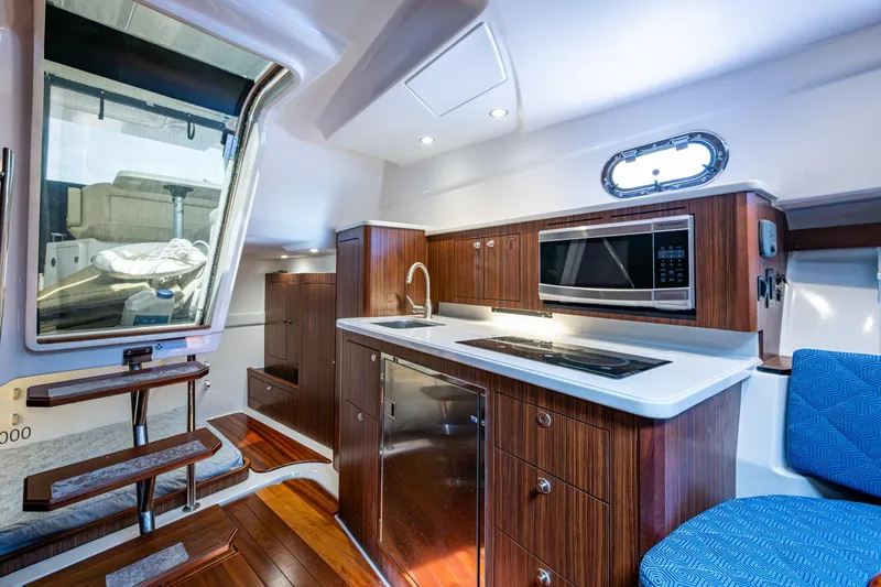  Yacht Photos Pics Luxurious Pursuit yacht interior with modern kitchen, wooden cabinetry, and sleek appliances.