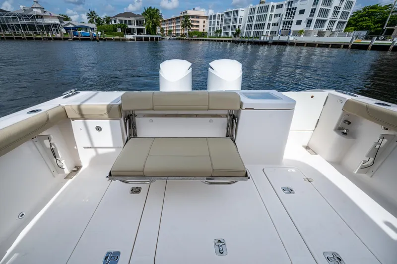  Yacht Photos Pics Spacious Pursuit boat deck with seating, overlooking waterfront buildings and calm water.
