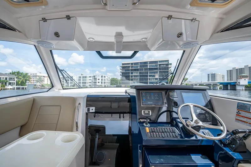  Yacht Photos Pics Interior view of a Pursuit boat cockpit with modern controls and waterfront cityscape.