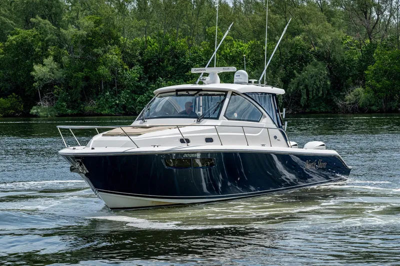  Yacht Photos Pics Pursuit boat cruising on a calm river with lush green trees in the background.