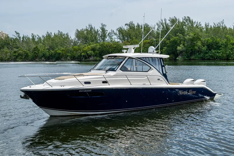  Yacht Photos Pics Pursuit boat "North Shore" cruising on a calm river with lush greenery.