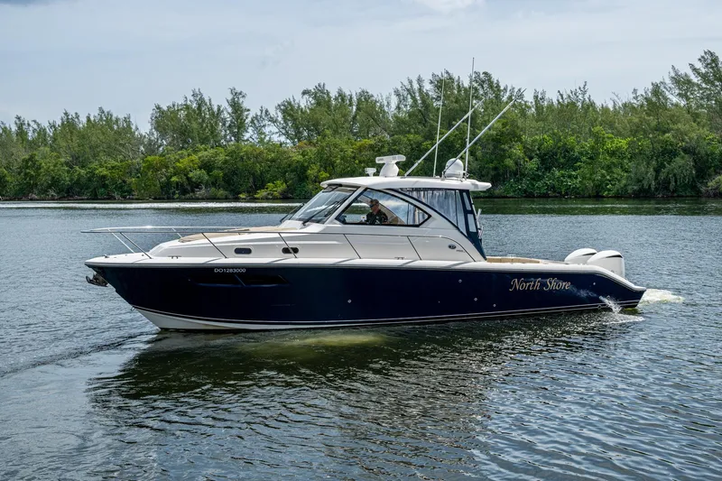  Yacht Photos Pics Pursuit boat "North Shore" cruising on a calm river with lush greenery.