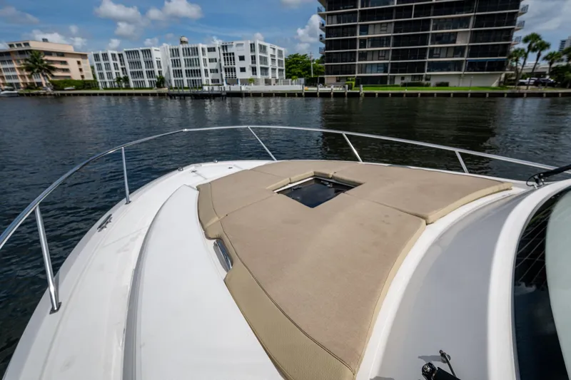  Yacht Photos Pics Bow of Pursuit boat with sunpad, overlooking waterfront buildings and calm water.