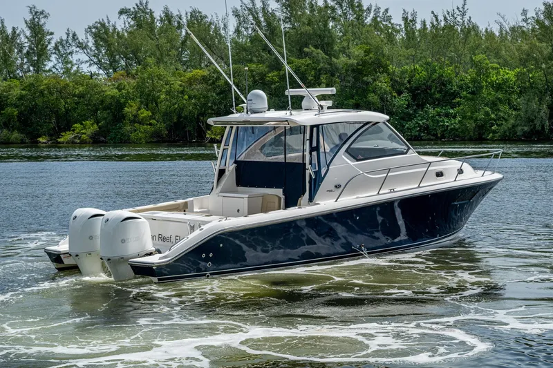  Yacht Photos Pics A Pursuit boat with dual engines cruising on a calm river, surrounded by lush greenery.