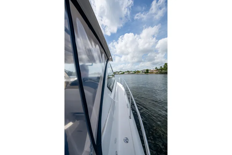  Yacht Photos Pics Side view of a Pursuit boat cruising on a calm waterway under a partly cloudy sky.