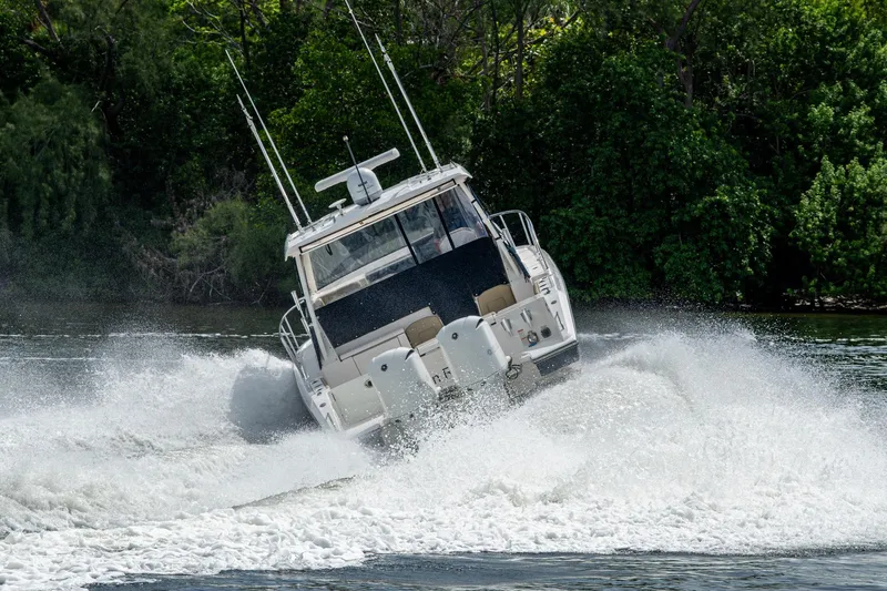  Yacht Photos Pics Powerful Pursuit boat navigating through water with lush green forest backdrop.