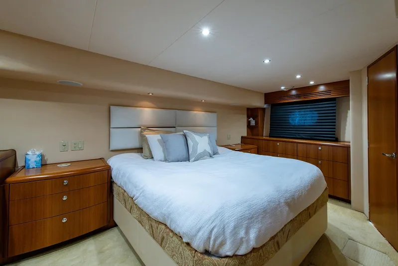  Yacht Photos Pics Luxurious bedroom interior of 2006 Hatteras 64 Convertible yacht with elegant wood furnishings.