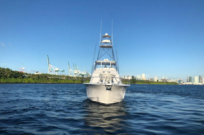  Yacht Photos Pics 2006 Hatteras 64 Convertible yacht on water with city skyline background.
