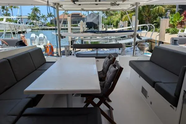 Sea Hugger Yacht Photos Pics Spacious deck of 2016 Nautitech 40 Open catamaran with seating and table, docked by waterfront.