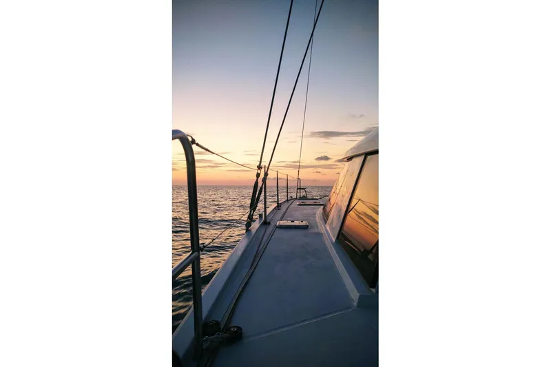 Sea Hugger Yacht Photos Pics Sailing on a 2016 Nautitech 40 Open catamaran at sunset over calm ocean waters.
