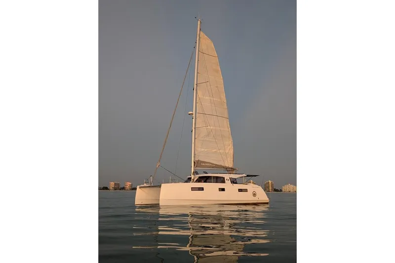 Sea Hugger Yacht Photos Pics Sailing catamaran Nautitech 40 Open 2016 on calm water, city skyline in background.