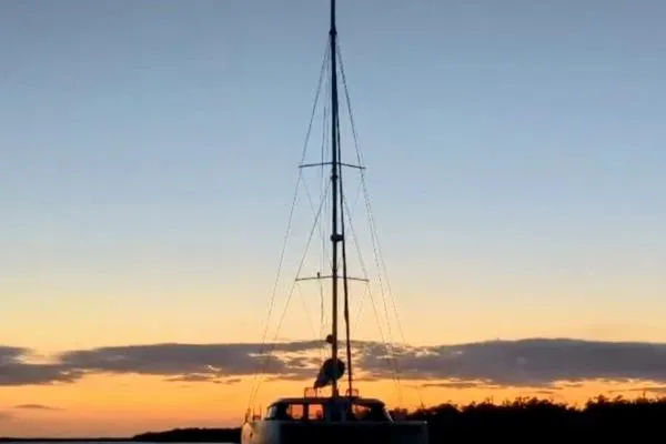 Sea Hugger Yacht Photos Pics Sailboat Nautitech 40 Open 2016 at sunset, silhouetted against a colorful sky.
