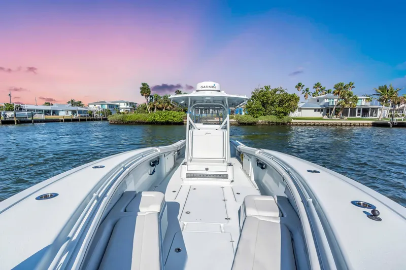 Yacht Photos Pics 2021 Yellowfin 36 Offshore boat on water at sunset, with coastal homes in background.