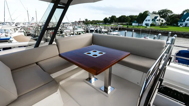  Yacht Photos Pics Flybridge seating area on 2019 Prestige 520 yacht, featuring a wooden table and marina view.