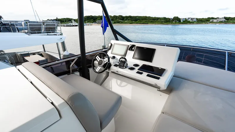  Yacht Photos Pics Flybridge helm of 2019 Prestige 520 yacht with modern navigation equipment, overlooking serene waters.