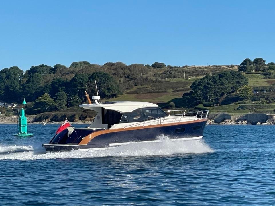 2025 Rustler 41 yacht cruising on a sunny day, with scenic coastal background.
