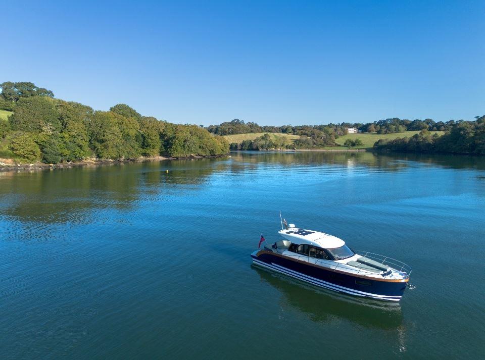 2025 Rustler 41 boat cruising on a serene lake with lush green surroundings.