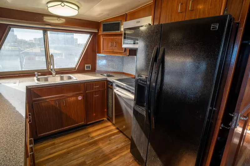 Hattrick Yacht Photos Pics 1981 Hatteras 61 Cockpit MY kitchen with wood cabinets, black appliances, and large windows.