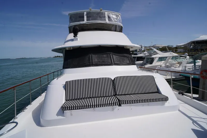 Hattrick Yacht Photos Pics 1981 Hatteras 61 Cockpit MY yacht with striped seating on deck, docked by the water.