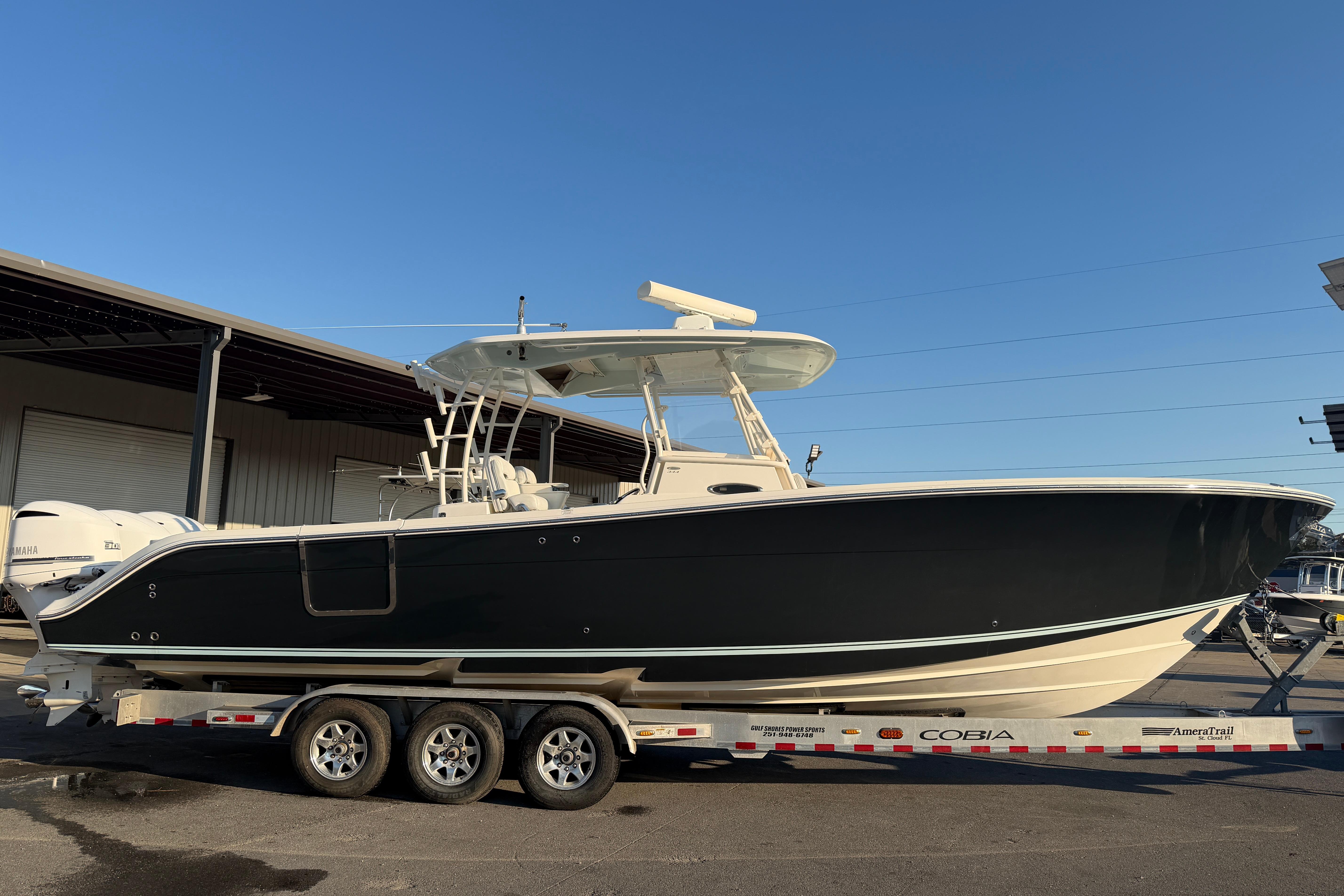 2015 Cobia 344 Center Console boat on trailer, parked outdoors under clear sky.