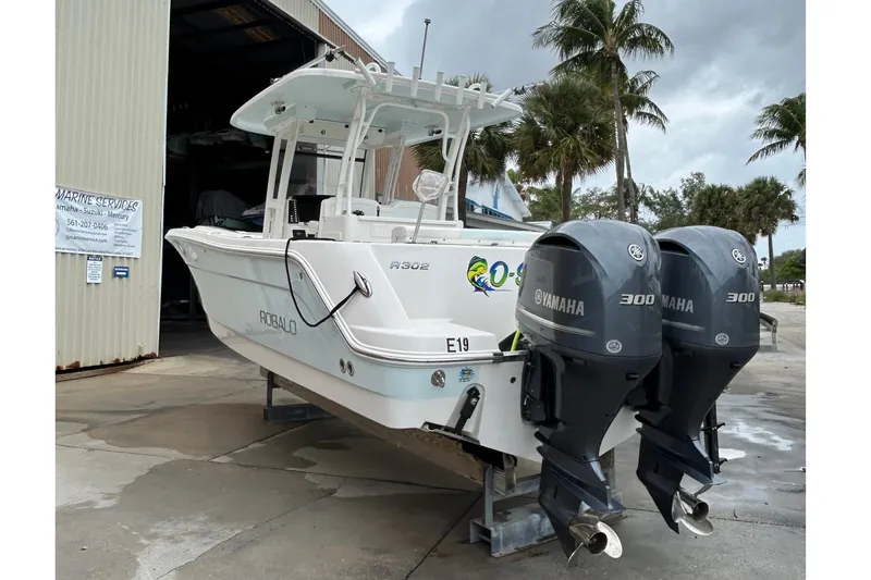  Yacht Photos Pics 2018 Robalo R302 Center Console boat with twin Yamaha 300 engines, docked near palm trees.