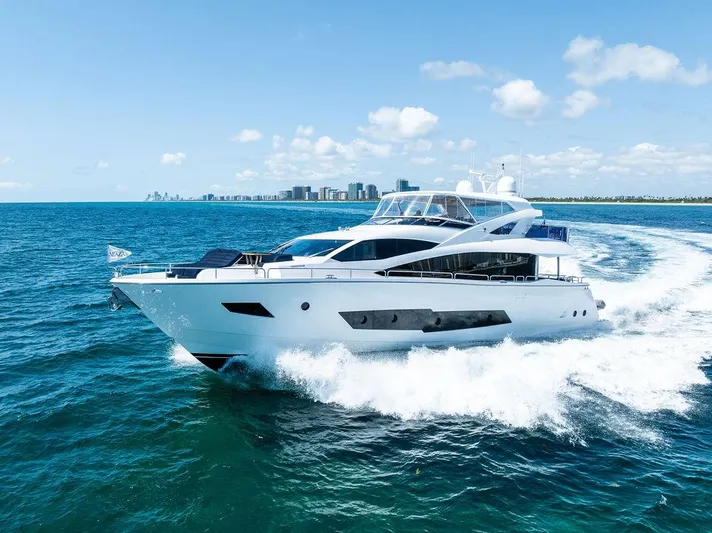 Sea Zar Yacht Photos Pics 2019 Sunseeker 86 Yacht cruising on open water with city skyline in background.