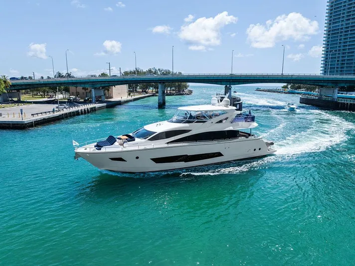 Sea Zar Yacht Photos Pics Luxurious 2019 Sunseeker 86 Yacht cruising under a bridge in clear blue waters.