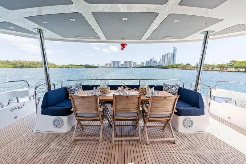 Sea Zar Yacht Photos Pics Luxurious 2019 Sunseeker 86 Yacht deck with dining area, overlooking serene waterfront cityscape.