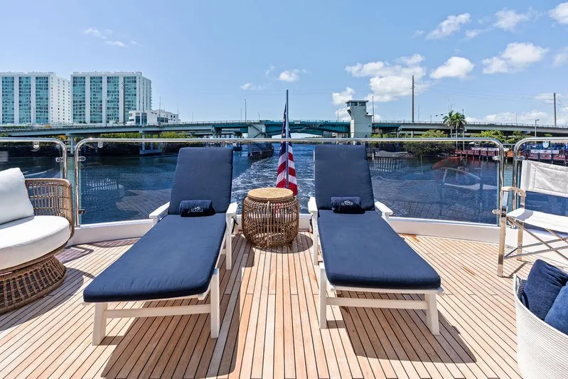 Sea Zar Yacht Photos Pics Sunseeker 86 Yacht 2019 deck with lounge chairs, American flag, and waterfront view.